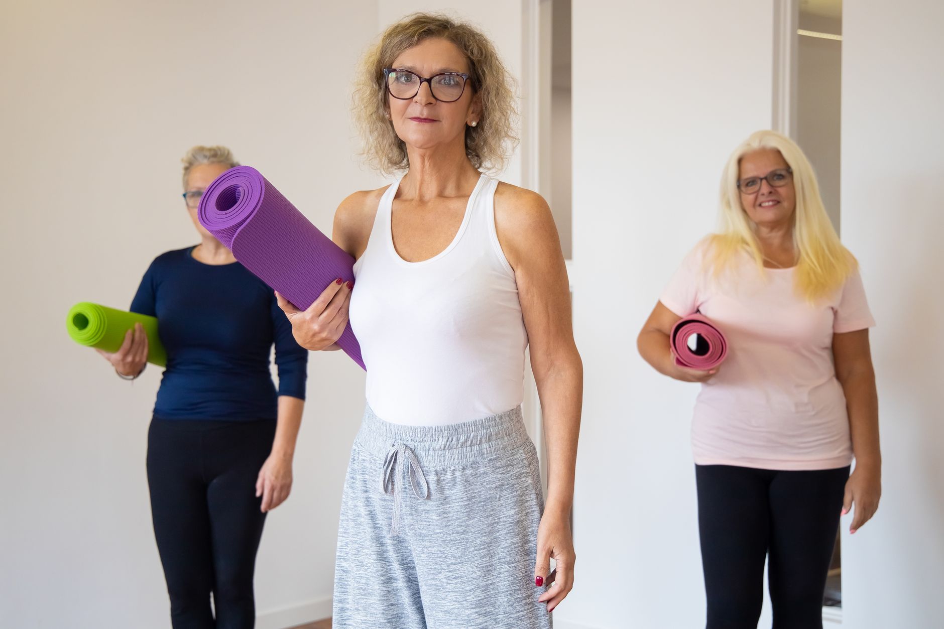 Trois femmes seniors tenant leur tapis avant un cours de gym douce