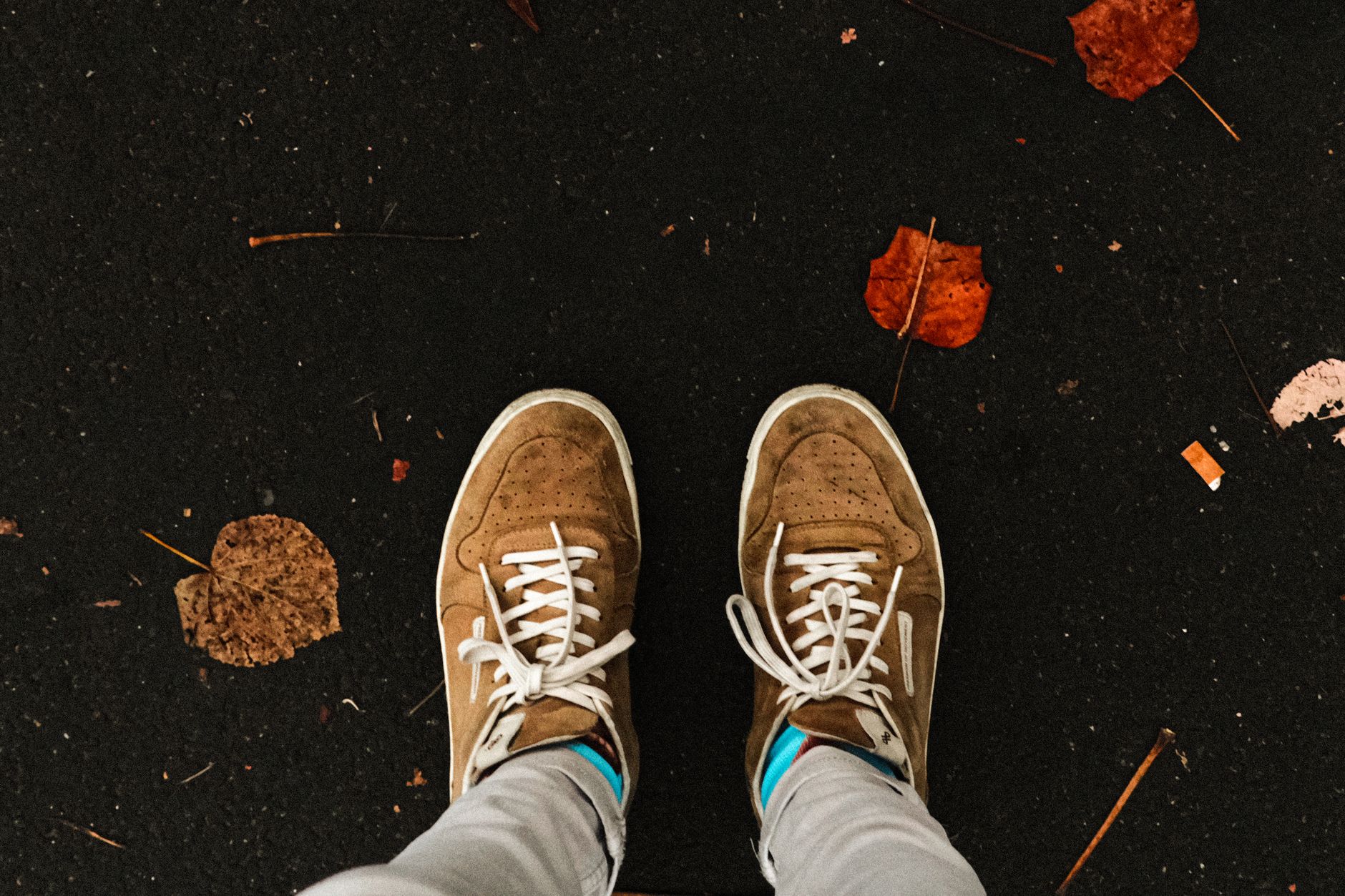 Baskets posées sur un trottoir jonché de feuilles d'automne