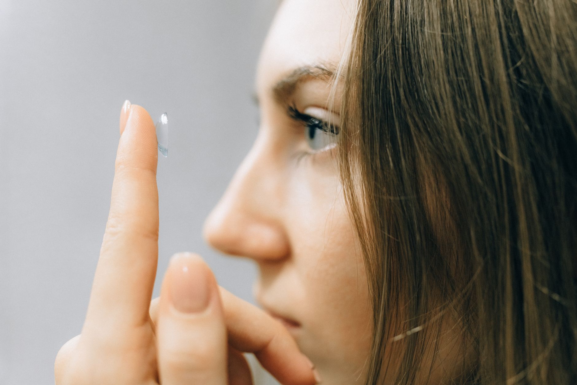 Une jeune femme pose une lentille de contact avec attention